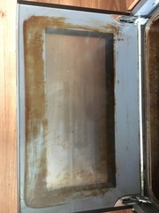 How can I clean my oven door glass?