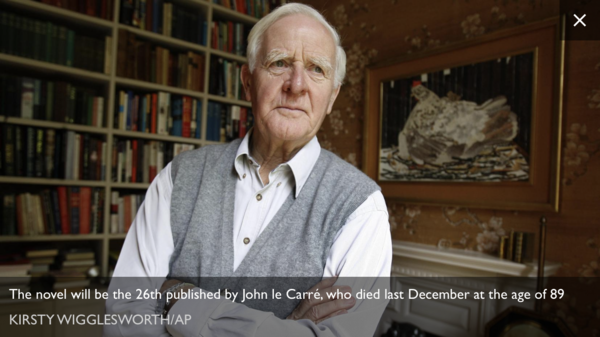 Why is John le Carre standing in front of a big chicken?