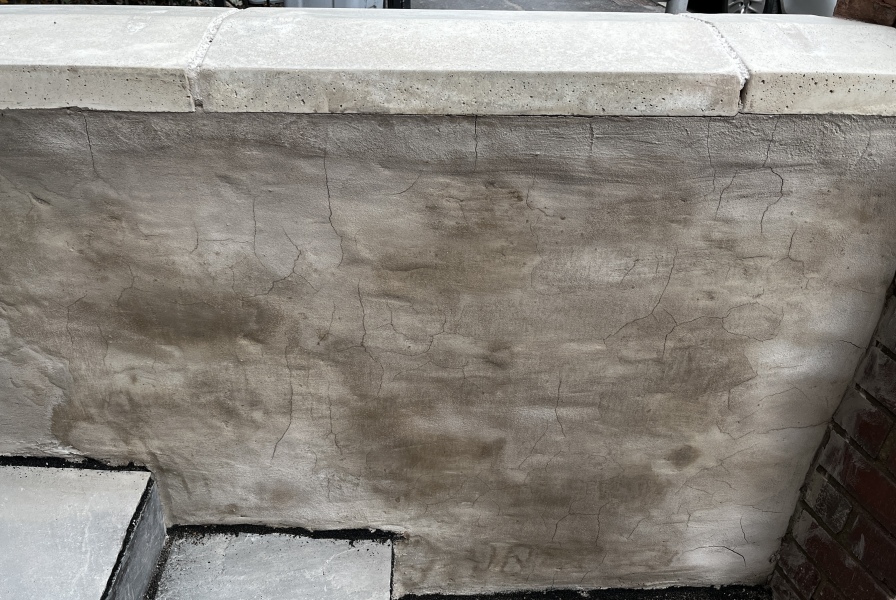Newly rendered garden wall - can we paint over the cracks?